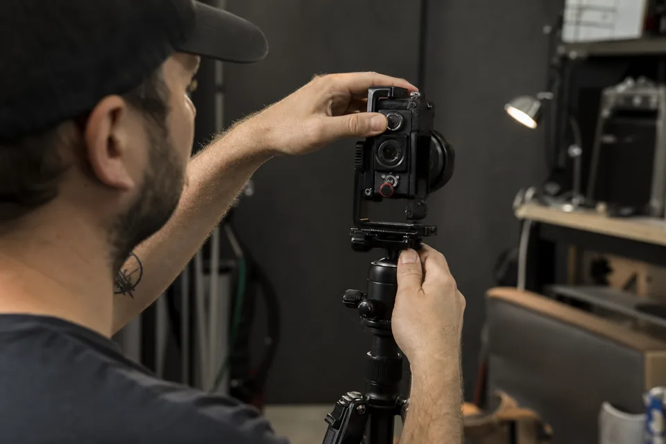 Hands rotating a camera on a tripod from horizontal to vertical