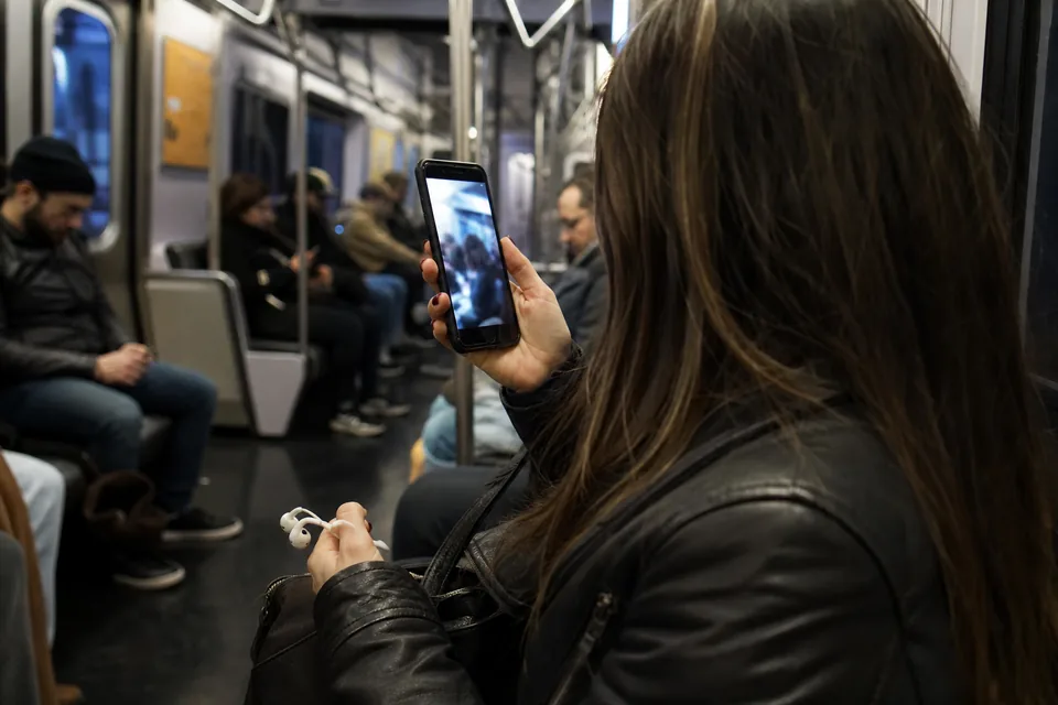 A commuter on a night train watching a vertical video with the sound off